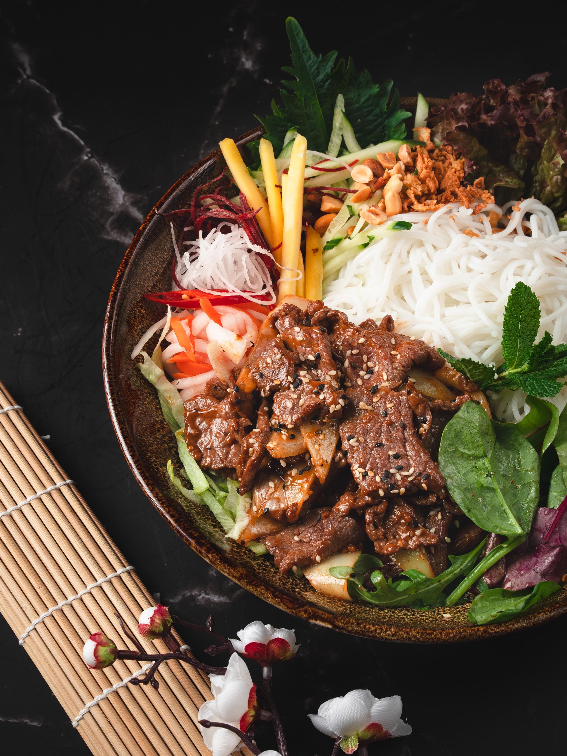 Asiatisches Gericht mit Reisnudeln und Beilagen